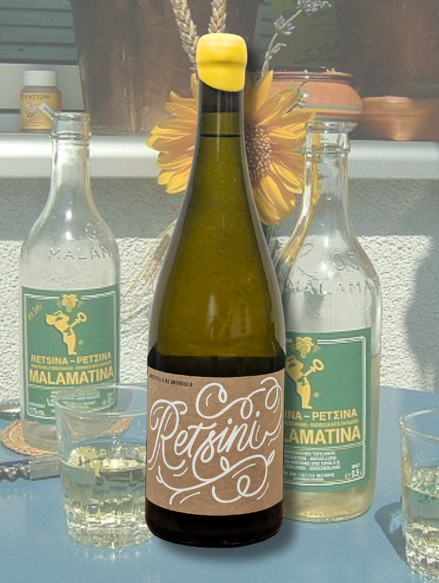 Aristotelis Ke Anthoula 'Retsini' Zibibbo 2023 bottle. Natural wine from Riverland, South Australia, made with skin-contact Zibibbo fermented on Aleppo pine resin. Background is old school Retsina bottles on a blue table with a sunflower.