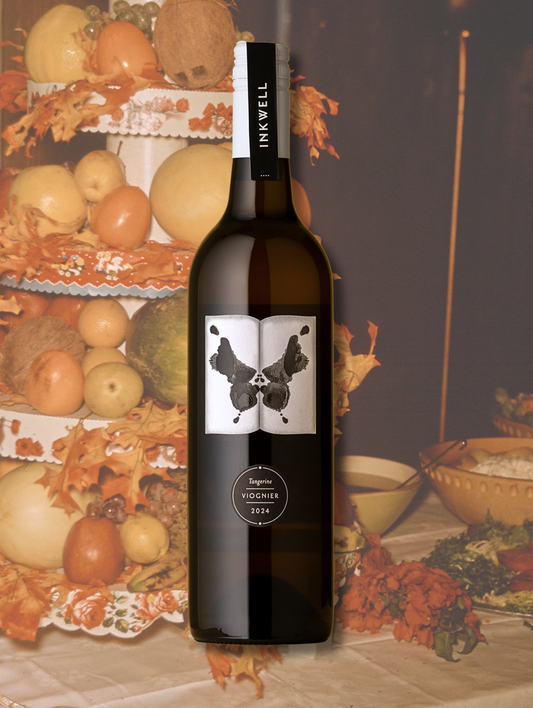 Inkwell 'Tangerine' Viognier 2024 bottle. Skin-contact Viognier from McLaren Vale, South Australia. Orange wine with medium body and stone fruit character. Background is a big fruit tower, still life style.