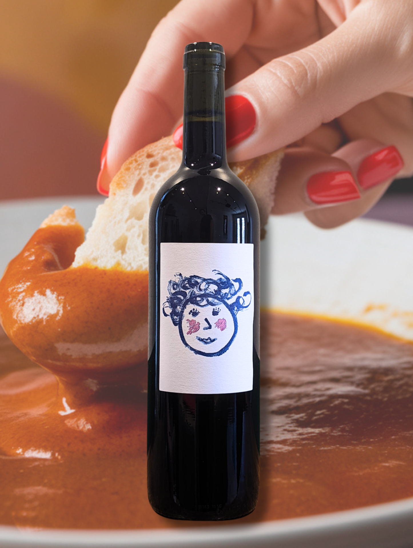 Bottle of Vita ‘Scarpetta’ Pinot Noir 2021 against a hand dipping a piece of bread into tomato pasta sauce