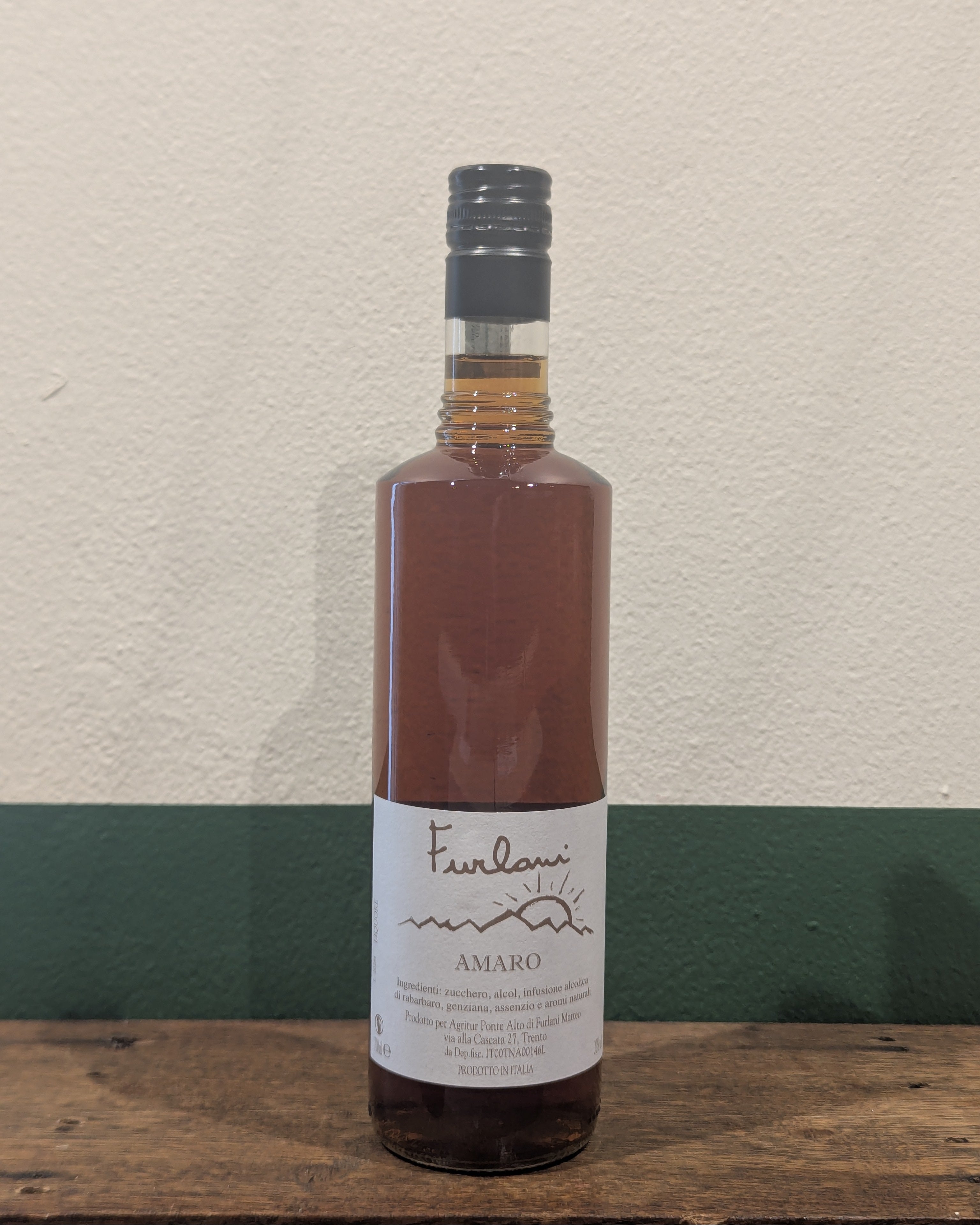 Bottle of Furlani Amaro on a wooden surface with a light background