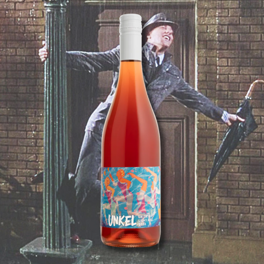 Unkel 'La De Da' Light Red 2022 bottle in front of the iconic ‘Singin’ in the Rain’ scene, emphasizing the wine’s playful, juicy, and expressive vibe. Light red wine with colourful label art.