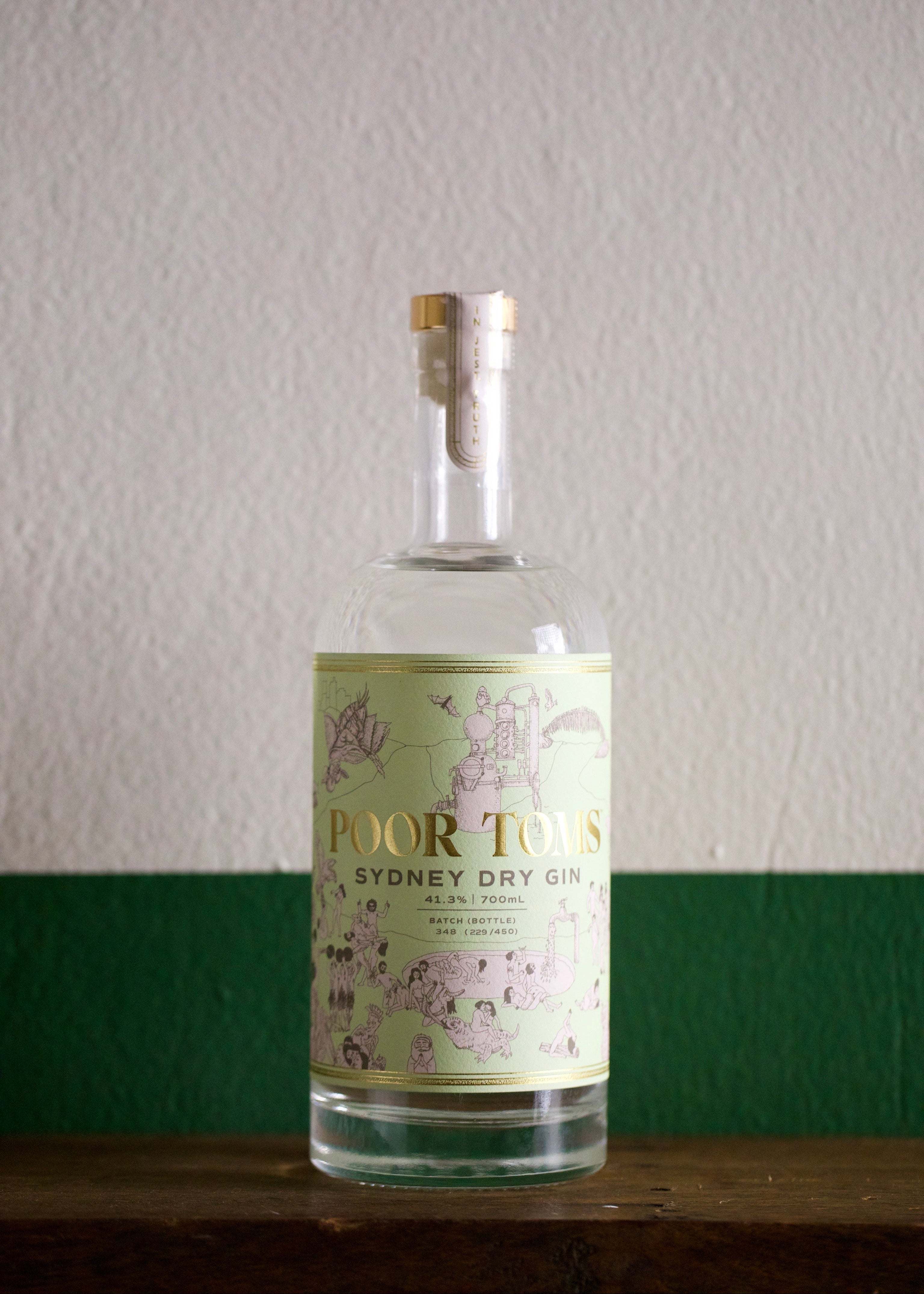 A bottle of Poor Tom's Sydney Dry Gin with a label showing botanical illustrations.